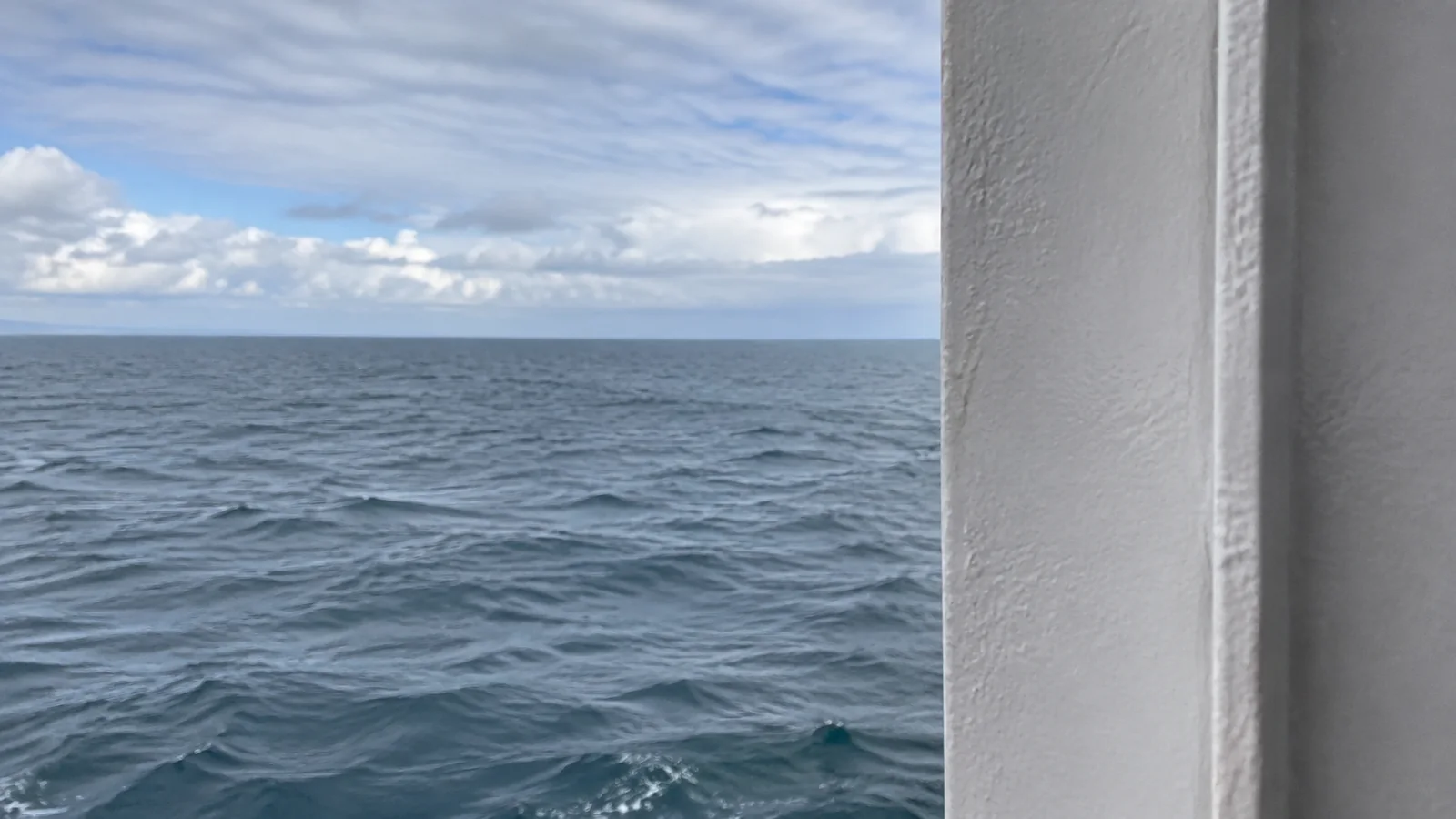 White structural panel narrows the sea view from a balcony.