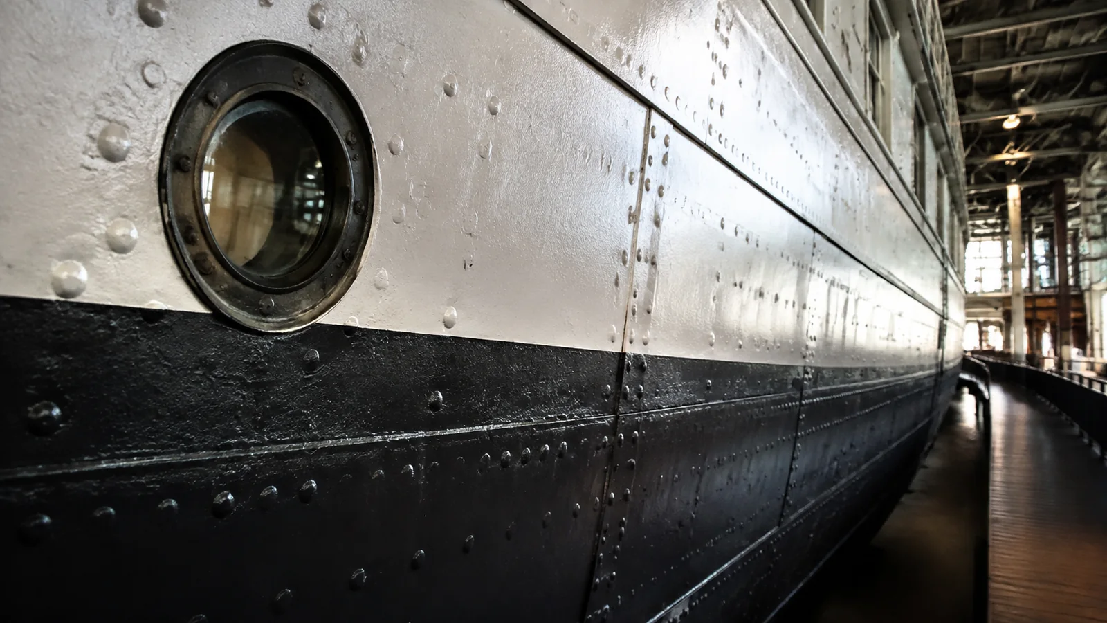 Round porthole in the riveted hull of a preserved ship.