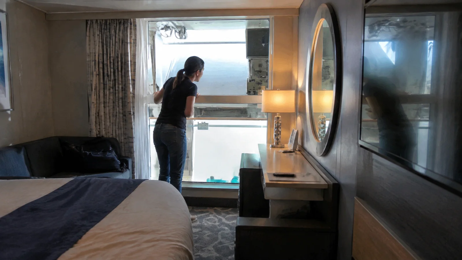 Woman looking through a cruise cabin window partly blocked by exterior equipment