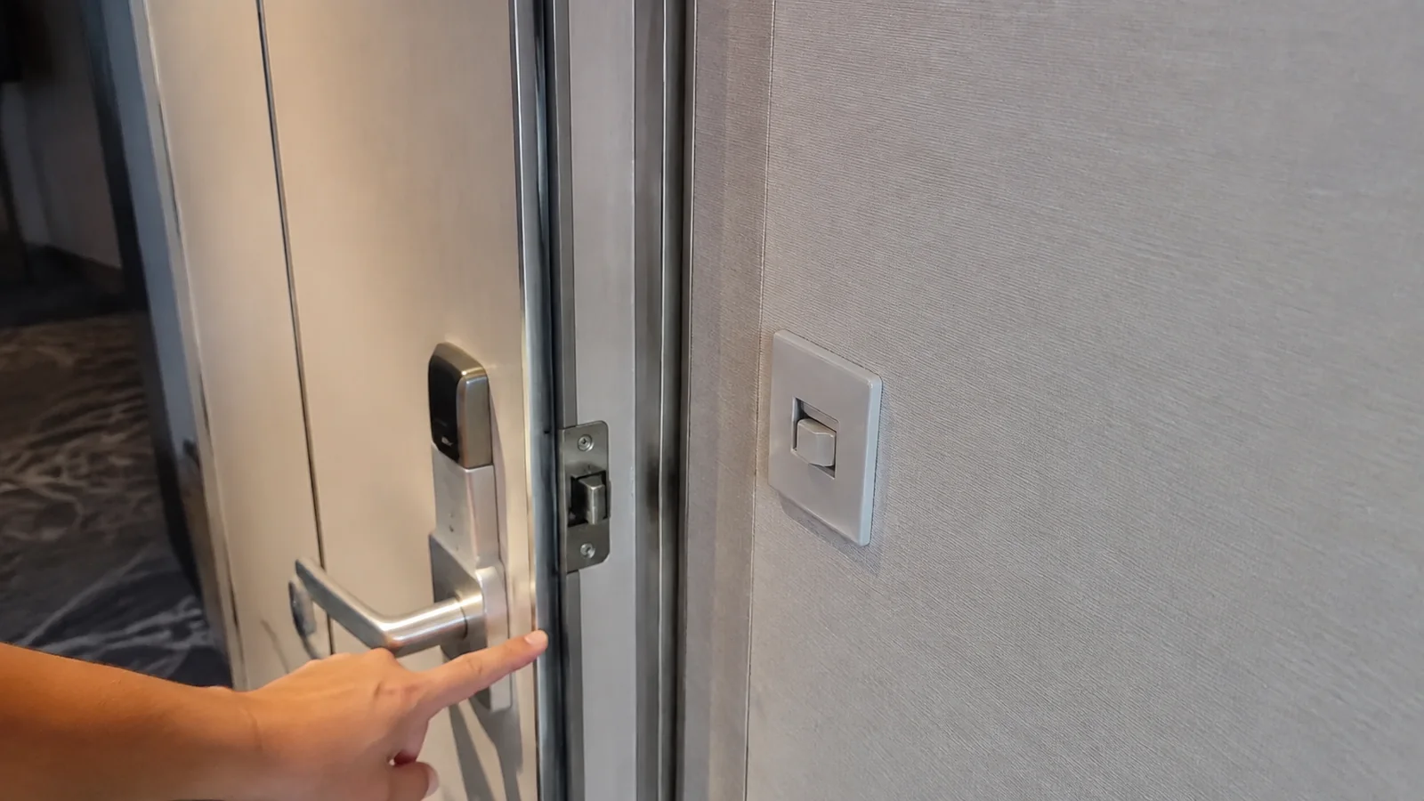 Hand pointing to a connecting door latch inside a cruise cabin