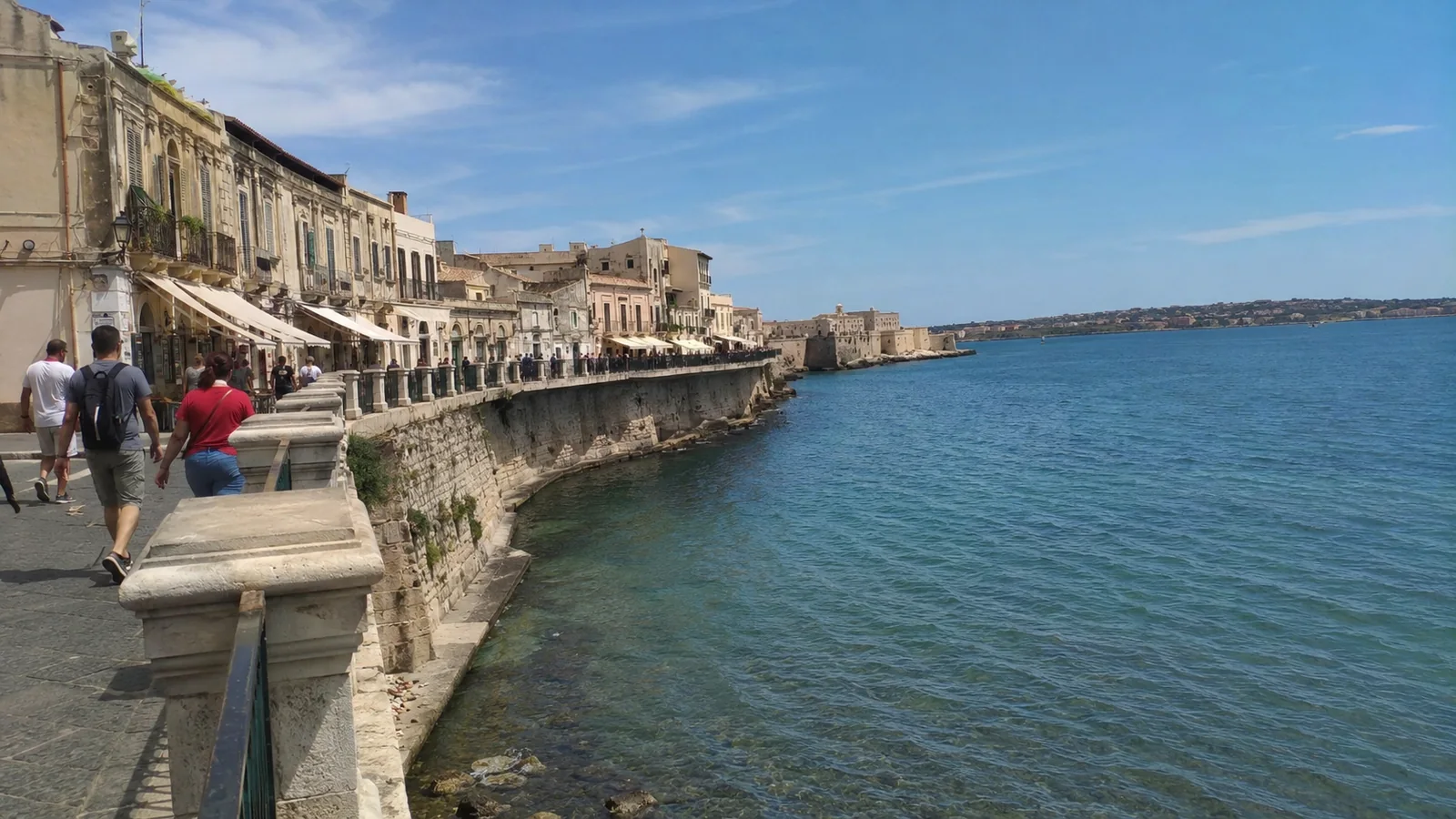 Historic stone waterfront promenade beside clear blue water