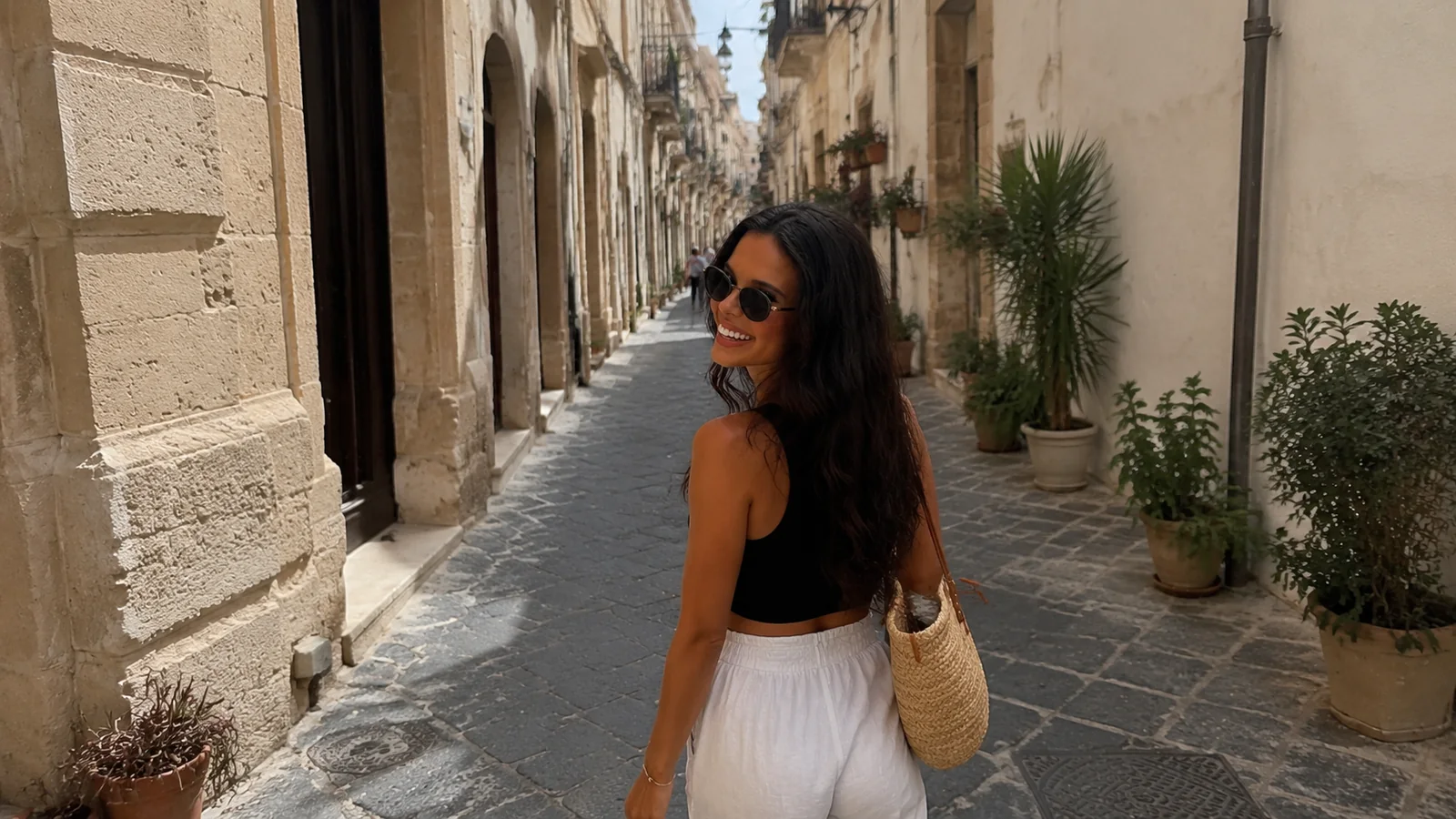 Smiling woman walking along a narrow stone street lined with historic buildings