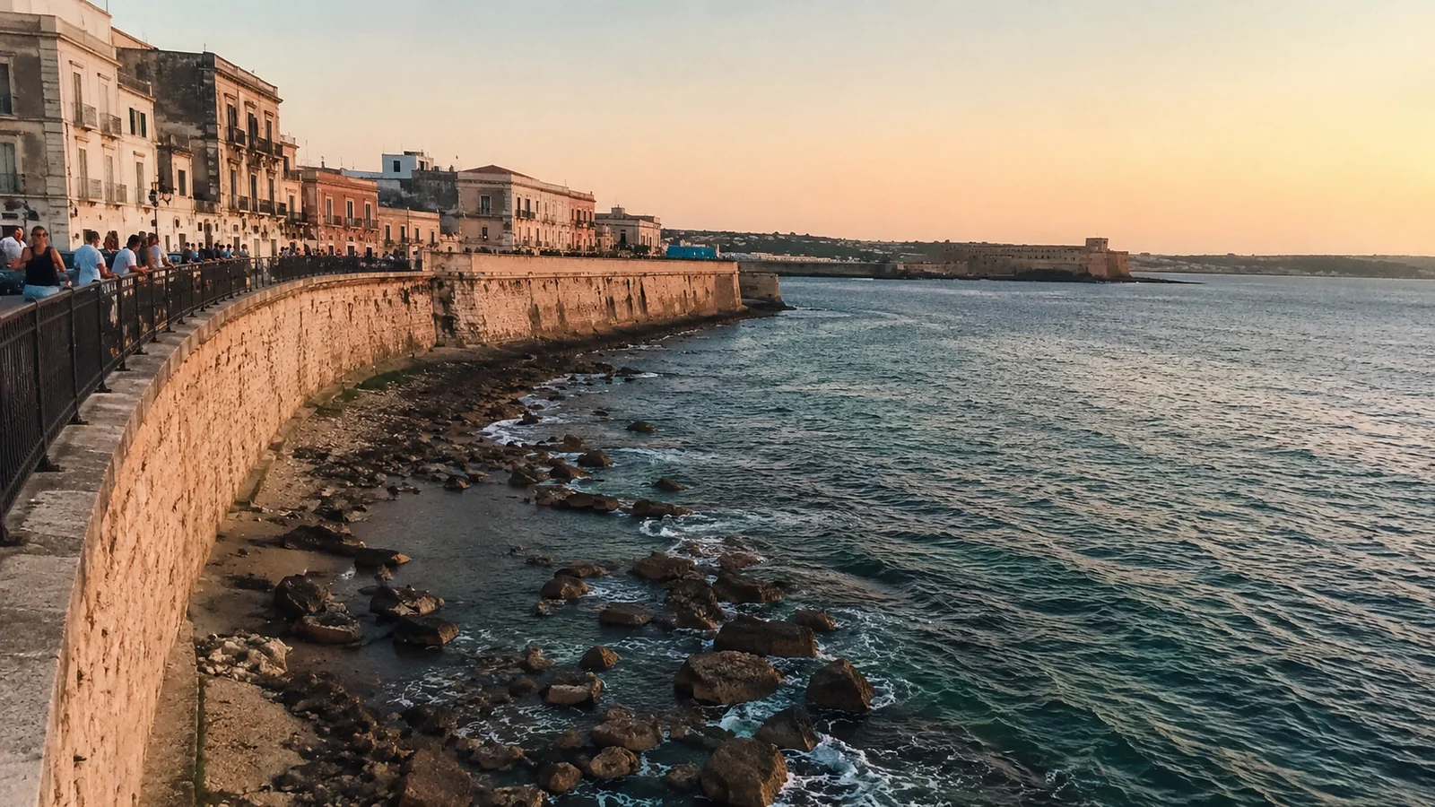 Stone seawall curving along a historic waterfront at sunset