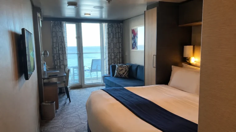 Balcony cabin with a double bed, blue sofa and desk.