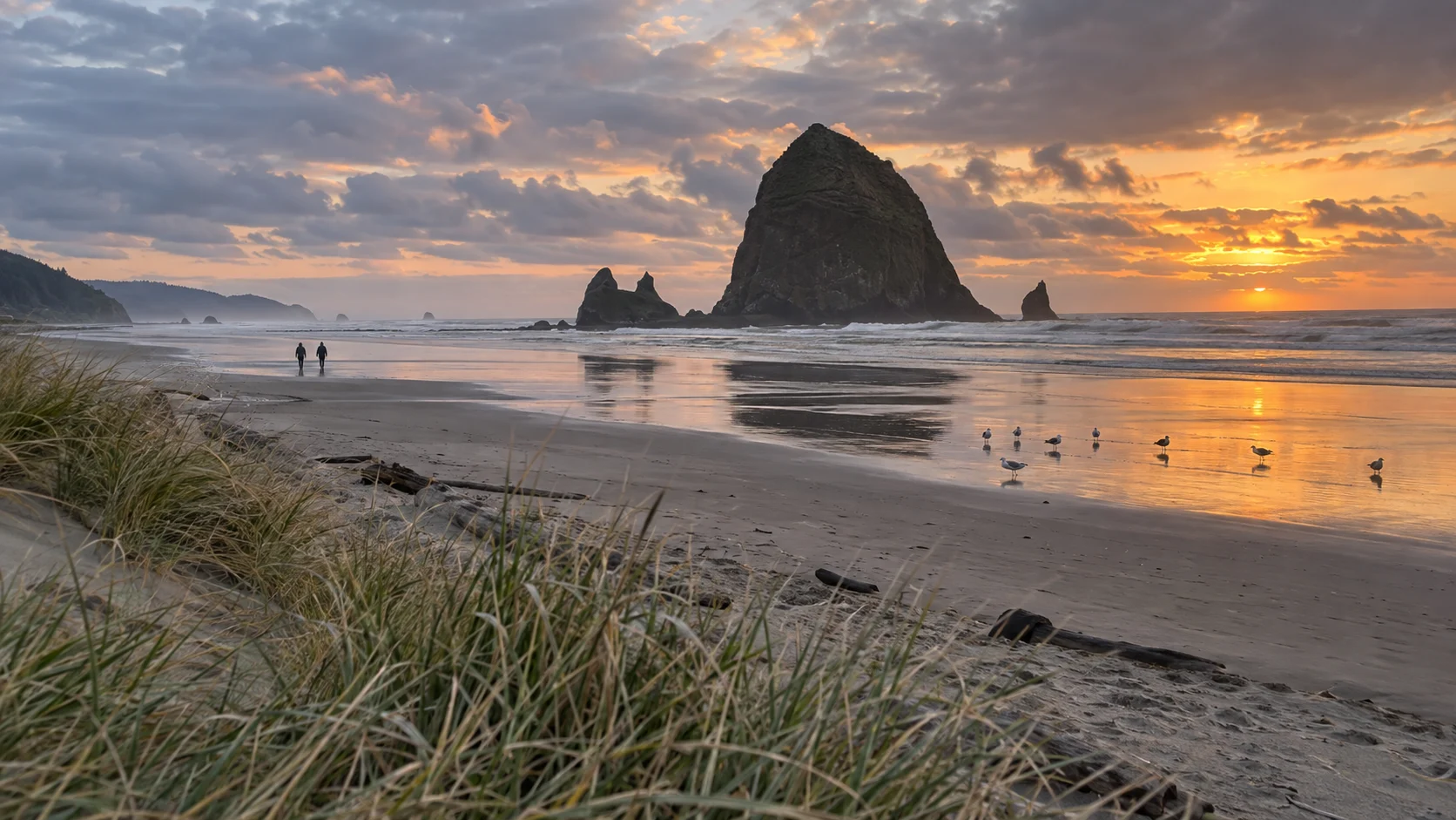 Haystack Rock reflected in the wet sand at Cannon Beach during sunset.