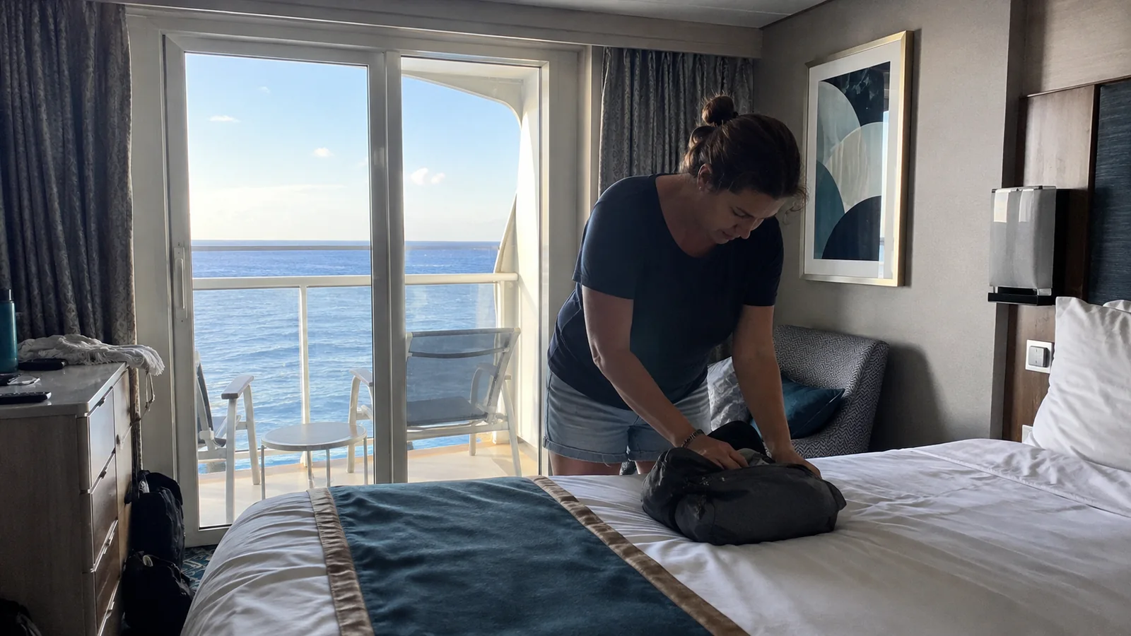Passenger unpacking a small bag on a balcony cabin bed.