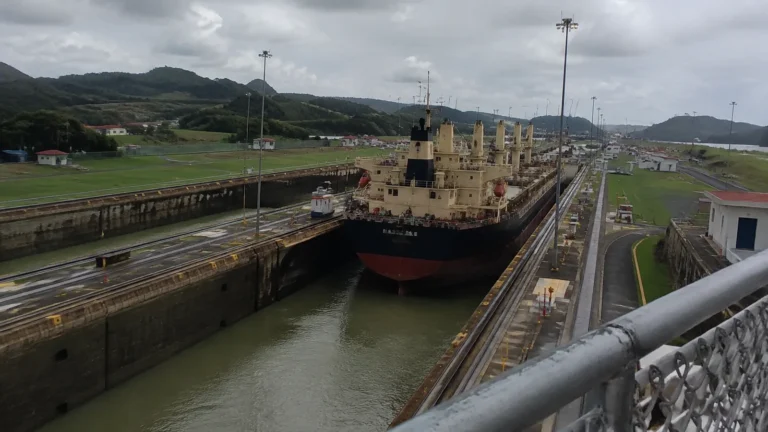 Cargo vessel inside a narrow canal lock surrounded by roads and grassy banks.