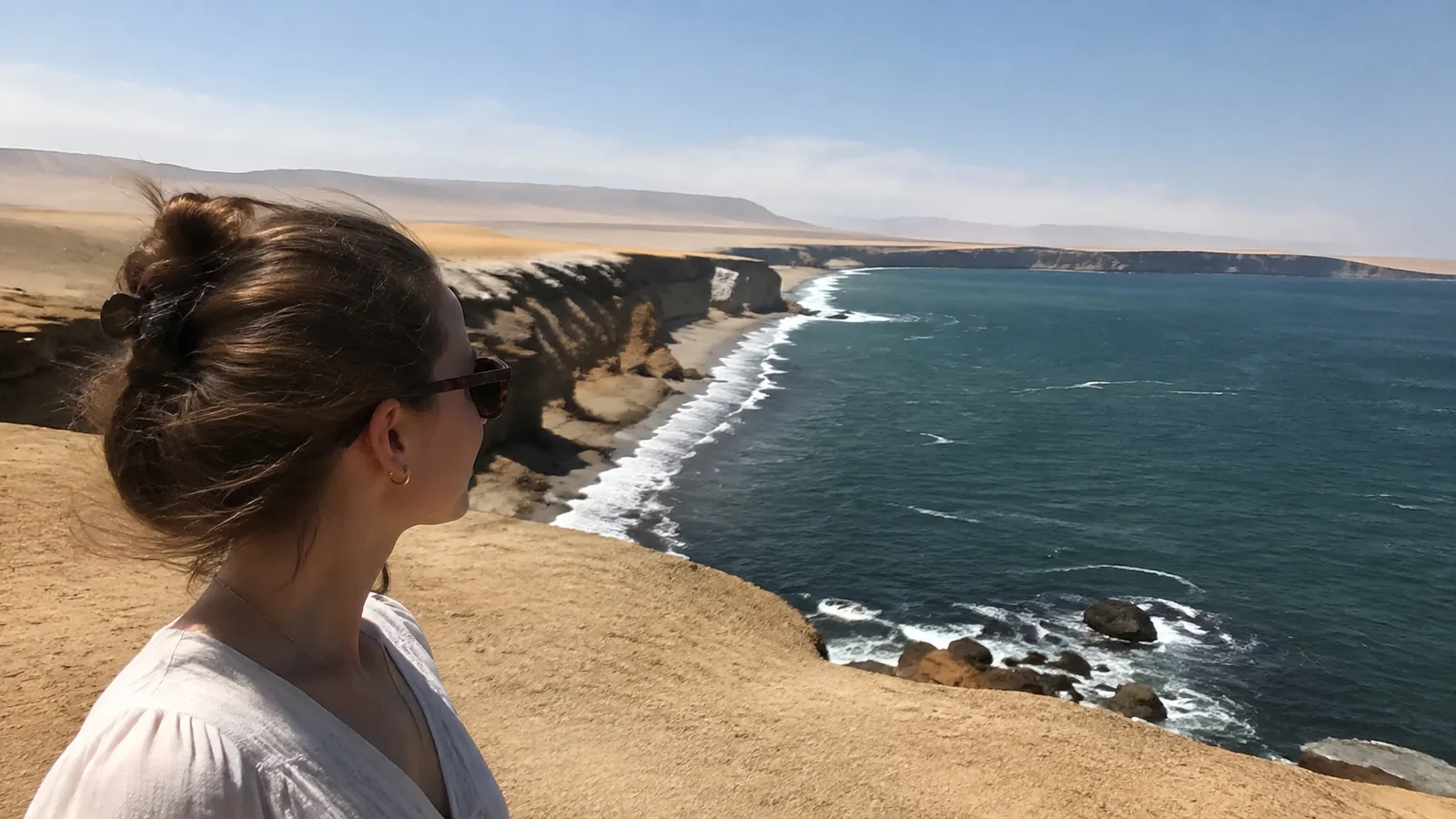 Traveler looking along desert cliffs above the Pacific coastline.