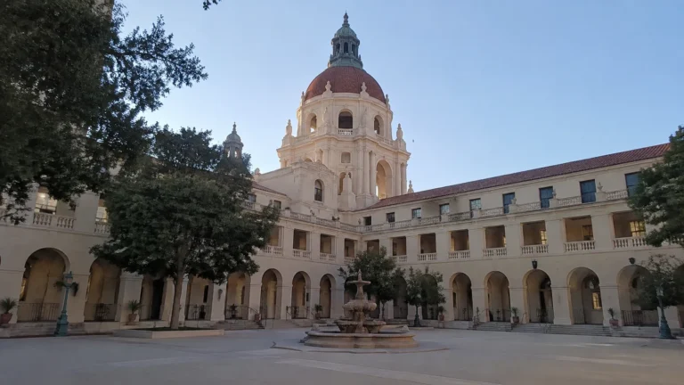 Domed civic building and arched courtyard beneath a clear blue sky.
