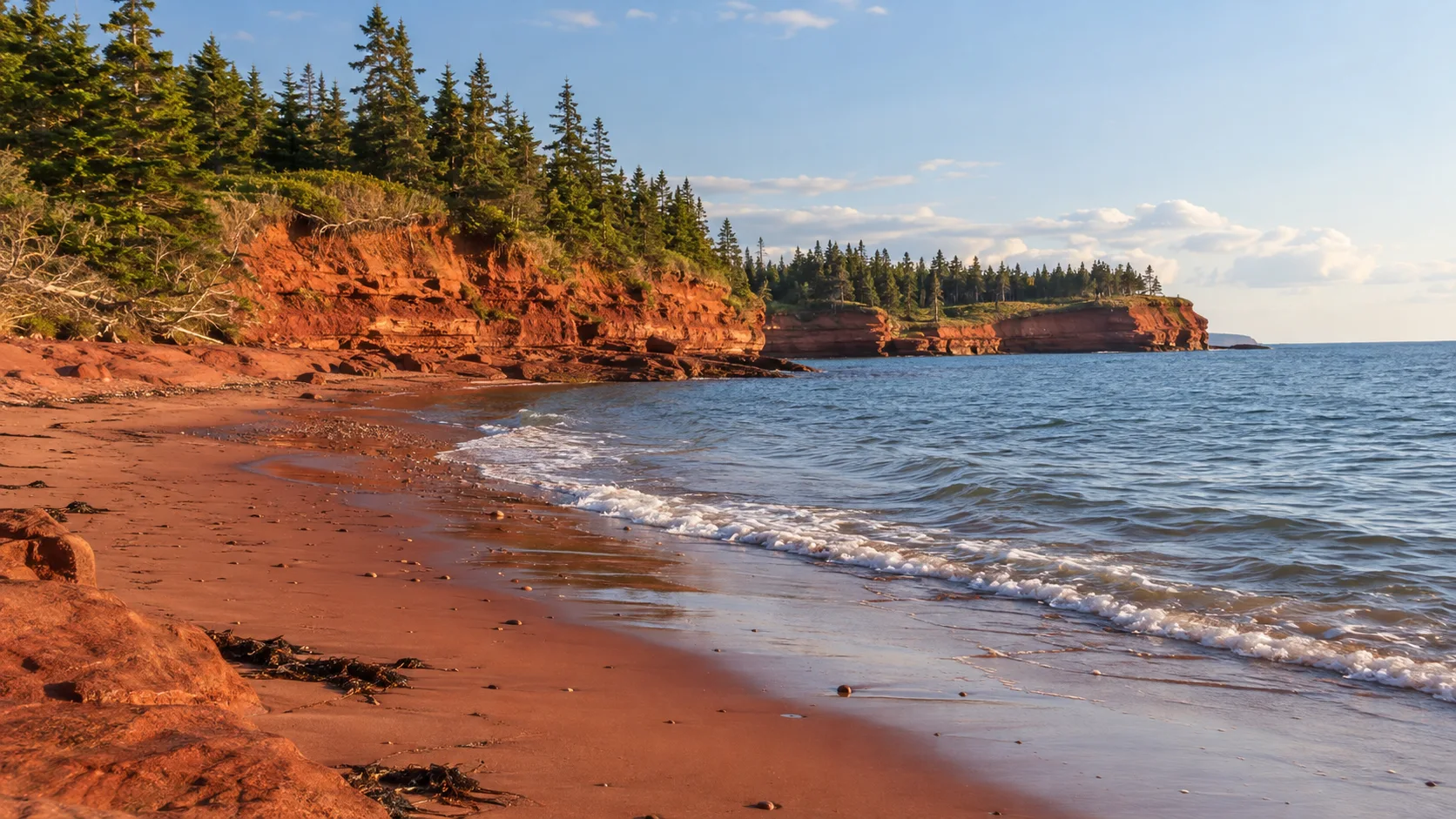 Low sandstone cliffs border the quiet red sand at Red Point Provincial Park.