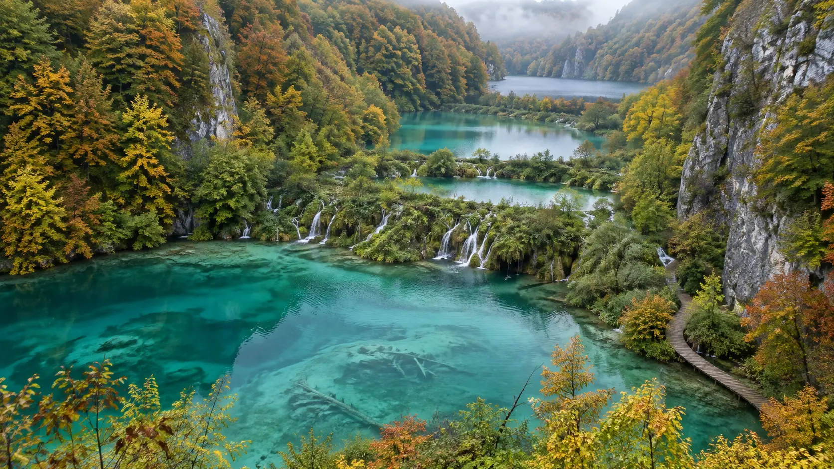 Connected turquoise lakes and delicate cascades surrounded by autumn forest at Plitvice.