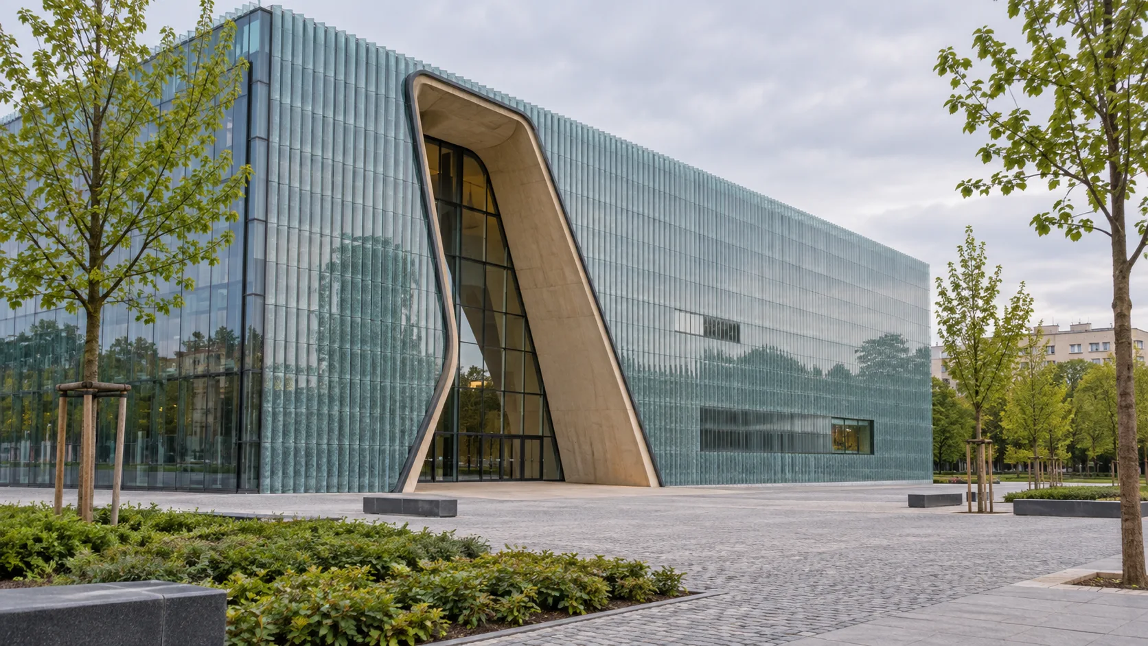 Curved glass entrance of the POLIN Museum across a quiet Warsaw plaza