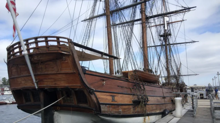 Historic wooden sailing ship with a raised stern deck and tall masts.