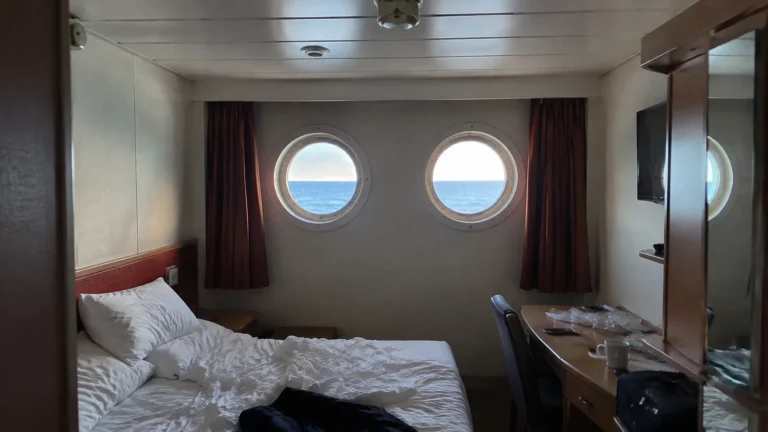 Cruise cabin with two round portholes above the bed.