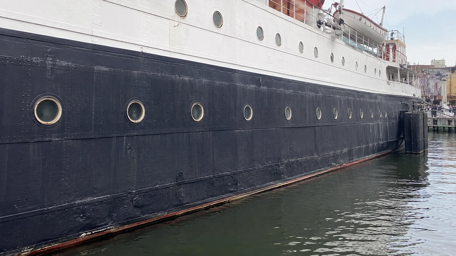 Rows of round portholes along a dark ship hull.