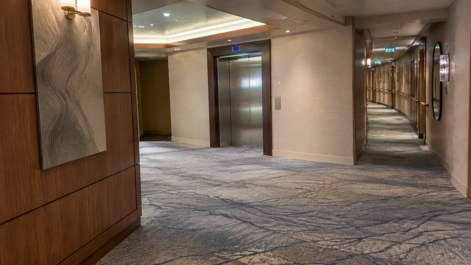 Closed cruise elevator doors stand beside an empty carpeted corridor.
