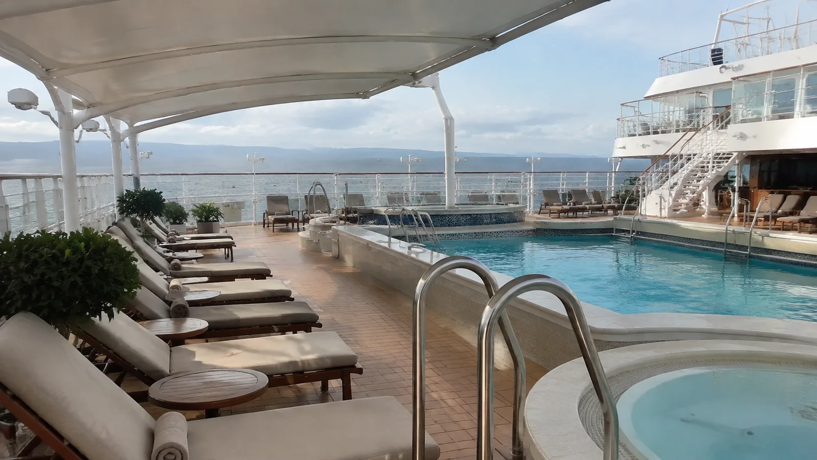 Quiet pool deck has cushioned loungers beneath a shade canopy.