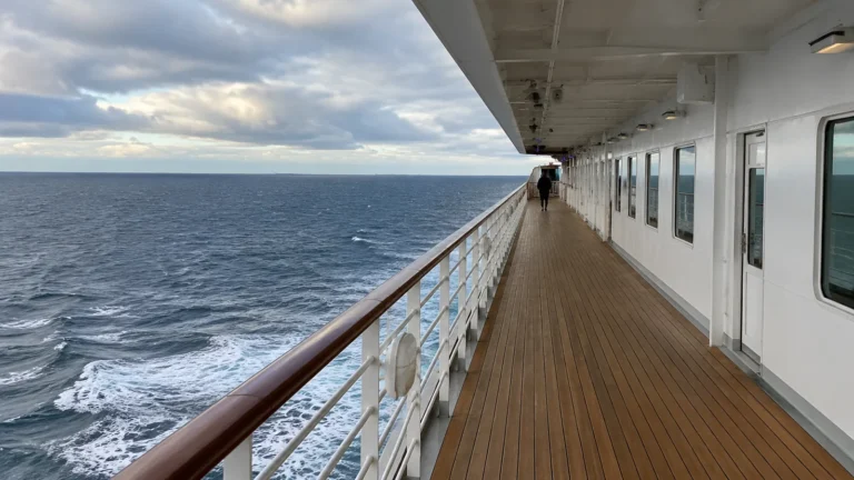 Empty cruise ship promenade deck overlooking the ocean under cloudy skies