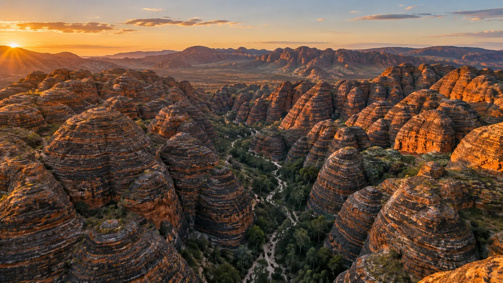 Striped sandstone domes fill Purnululu National Park beneath warm Kimberley sunrise light.