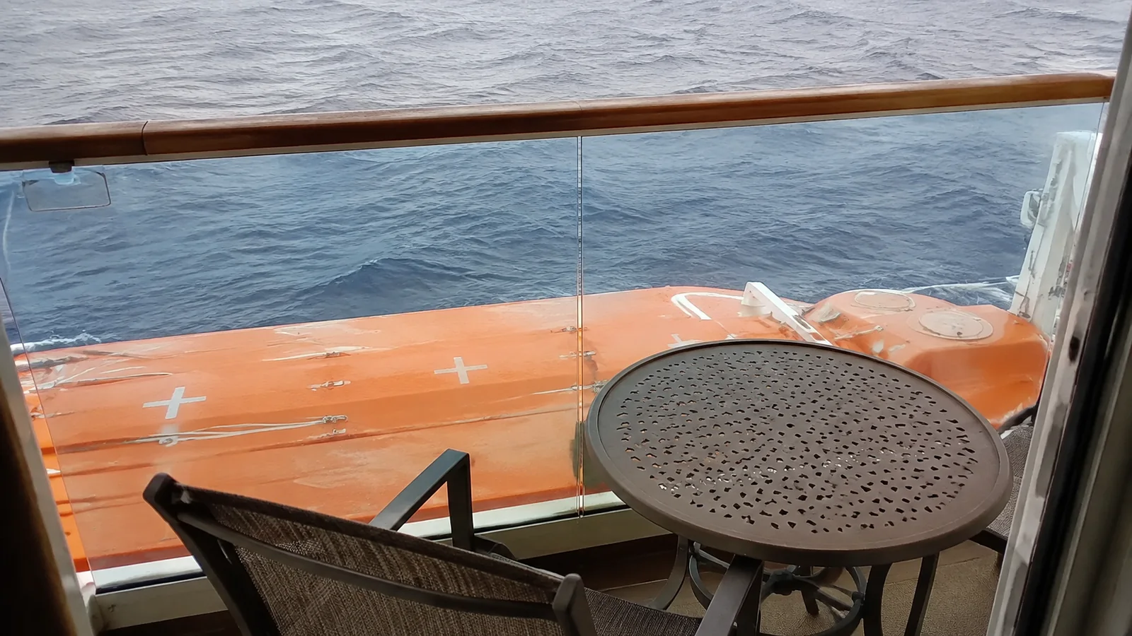 Balcony table and chairs positioned above an orange lifeboat.
