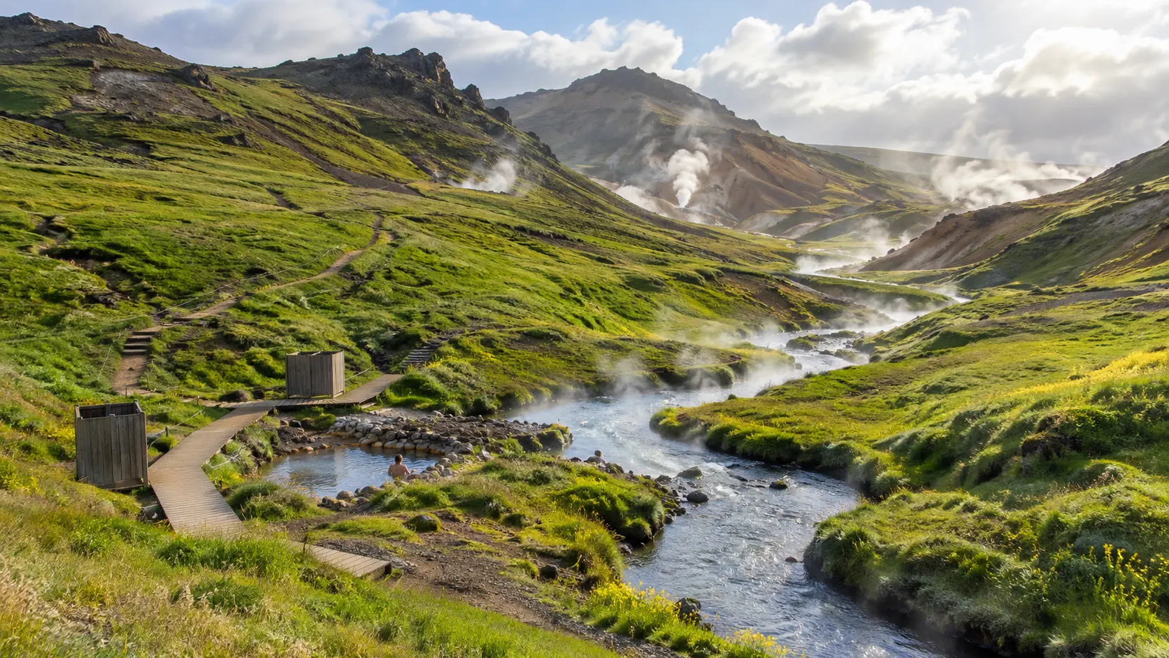 Steaming Reykjadalur hot river winding through a green Icelandic valley