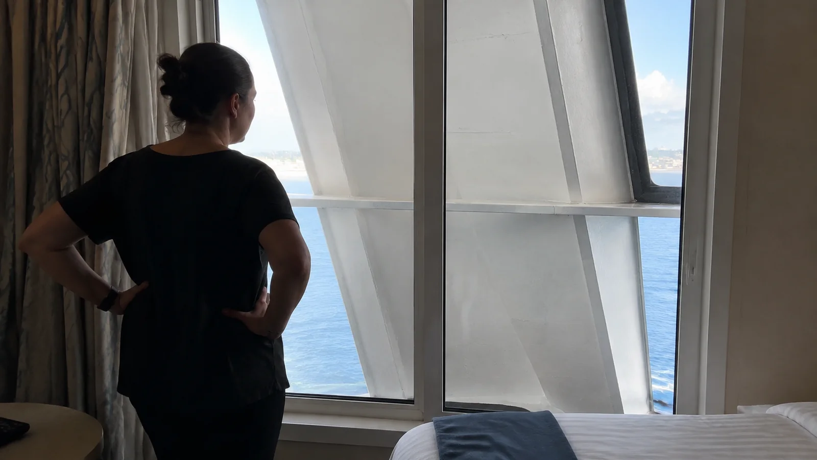 Woman facing a cruise cabin window partly blocked by a large diagonal support