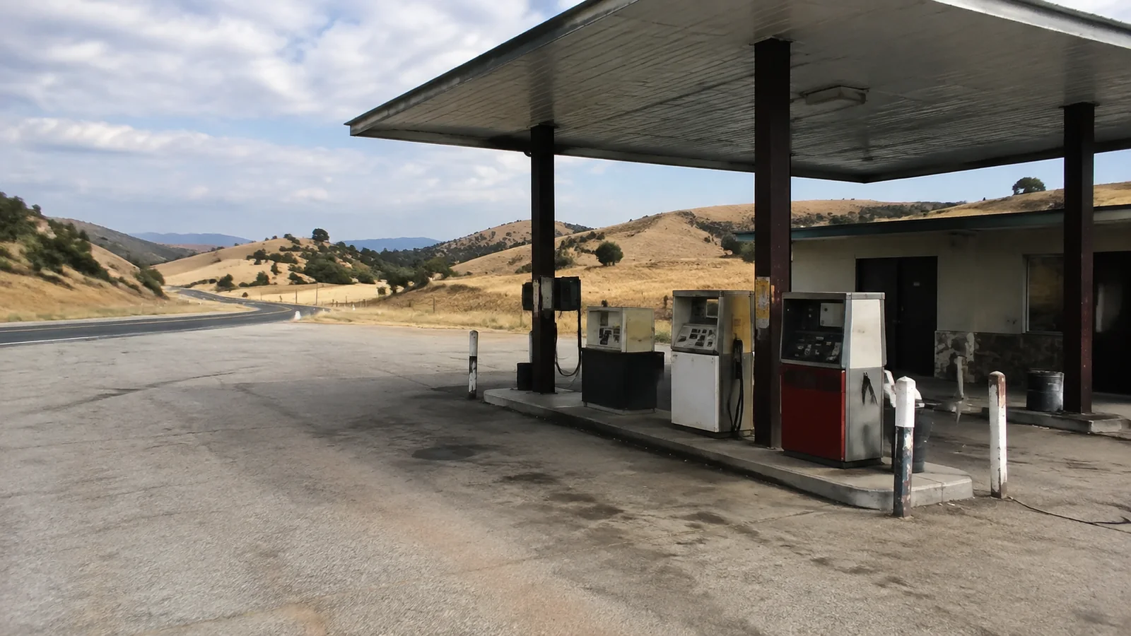 Remote fuel pumps stand beneath a canopy in dry rolling countryside.