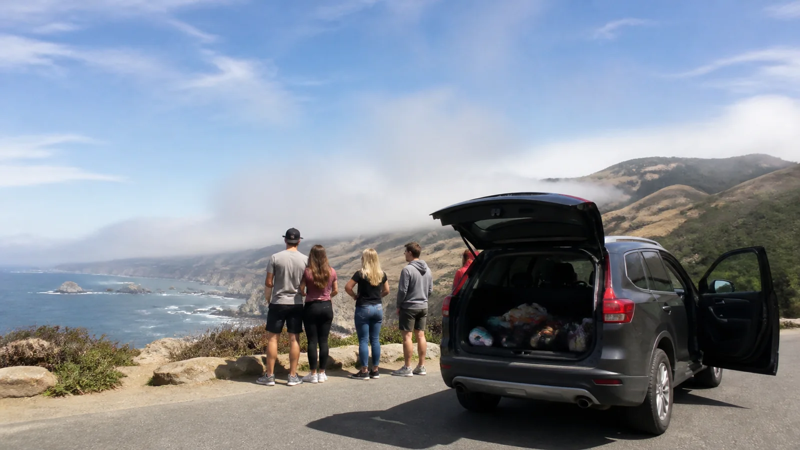 Travelers admiring a coastal view beside an SUV with its hatch open