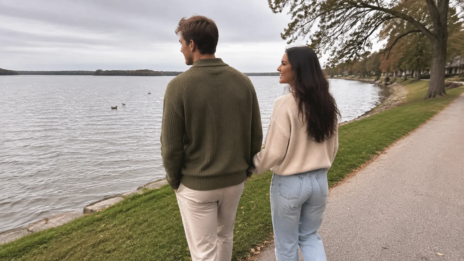 Couple walking together along a lakeside path.