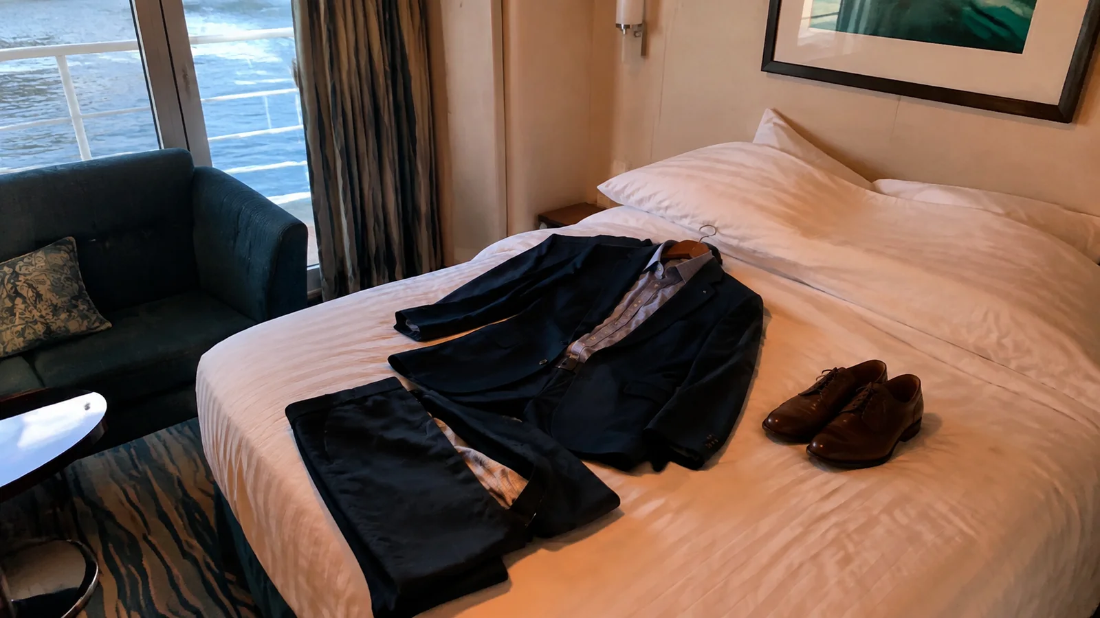 Dark suit, tie and leather shoes arranged on a cabin bed.