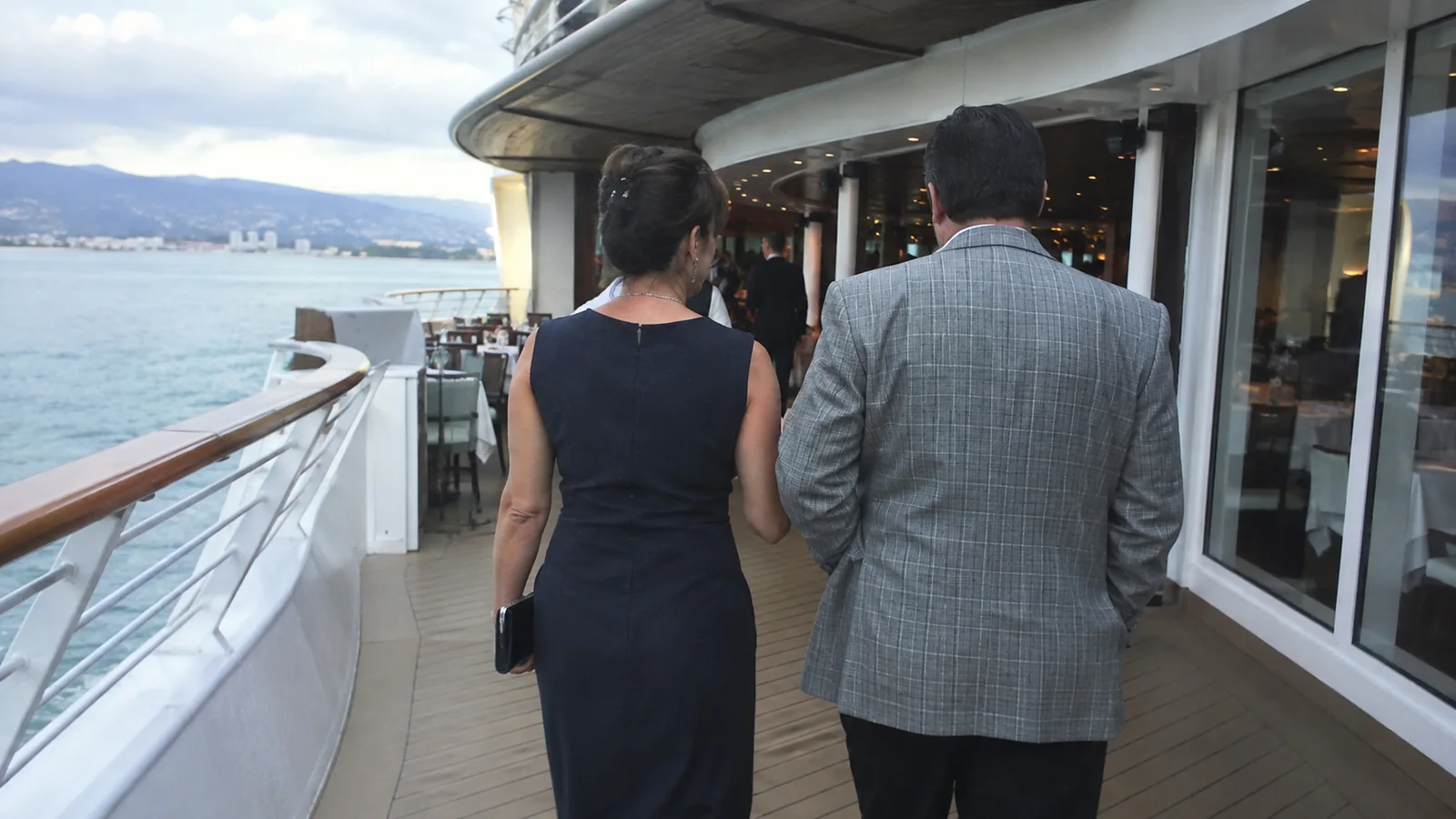 Couple in evening clothes walking along an outdoor ship terrace.