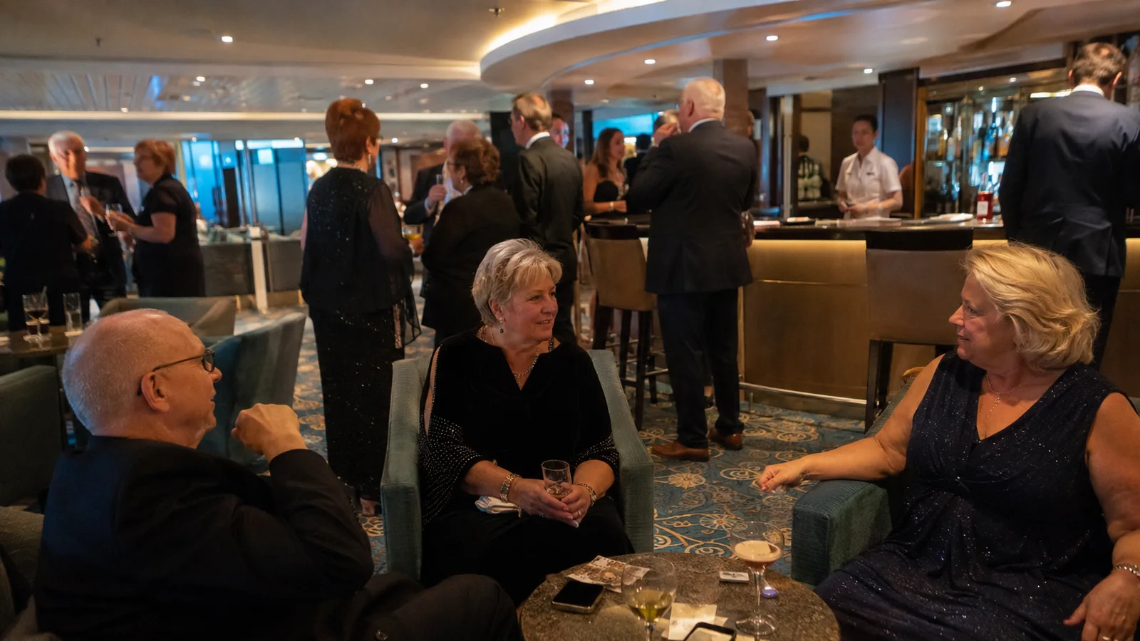 Passengers in formal clothes socializing in a ship lounge.