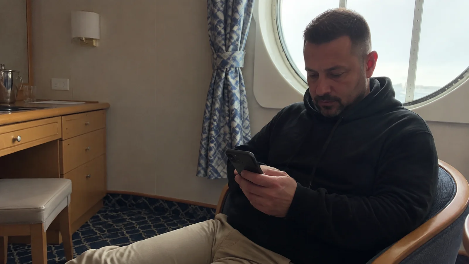 Passenger checking his phone while seated in a cabin.