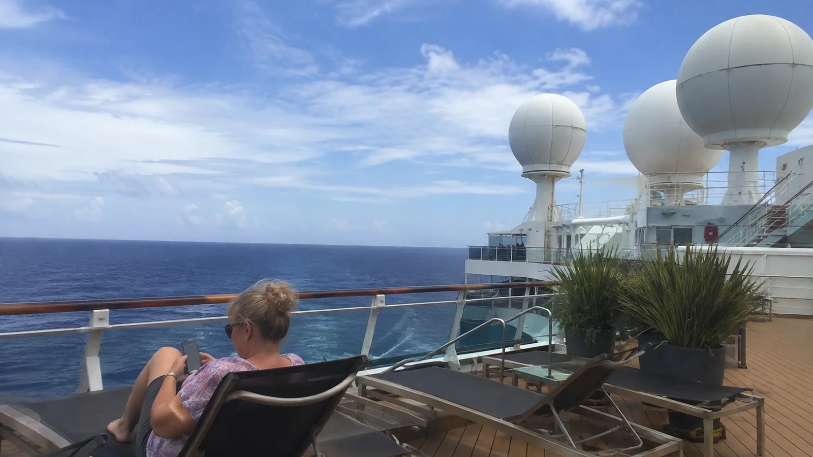 Passenger reclining on deck near satellite domes.