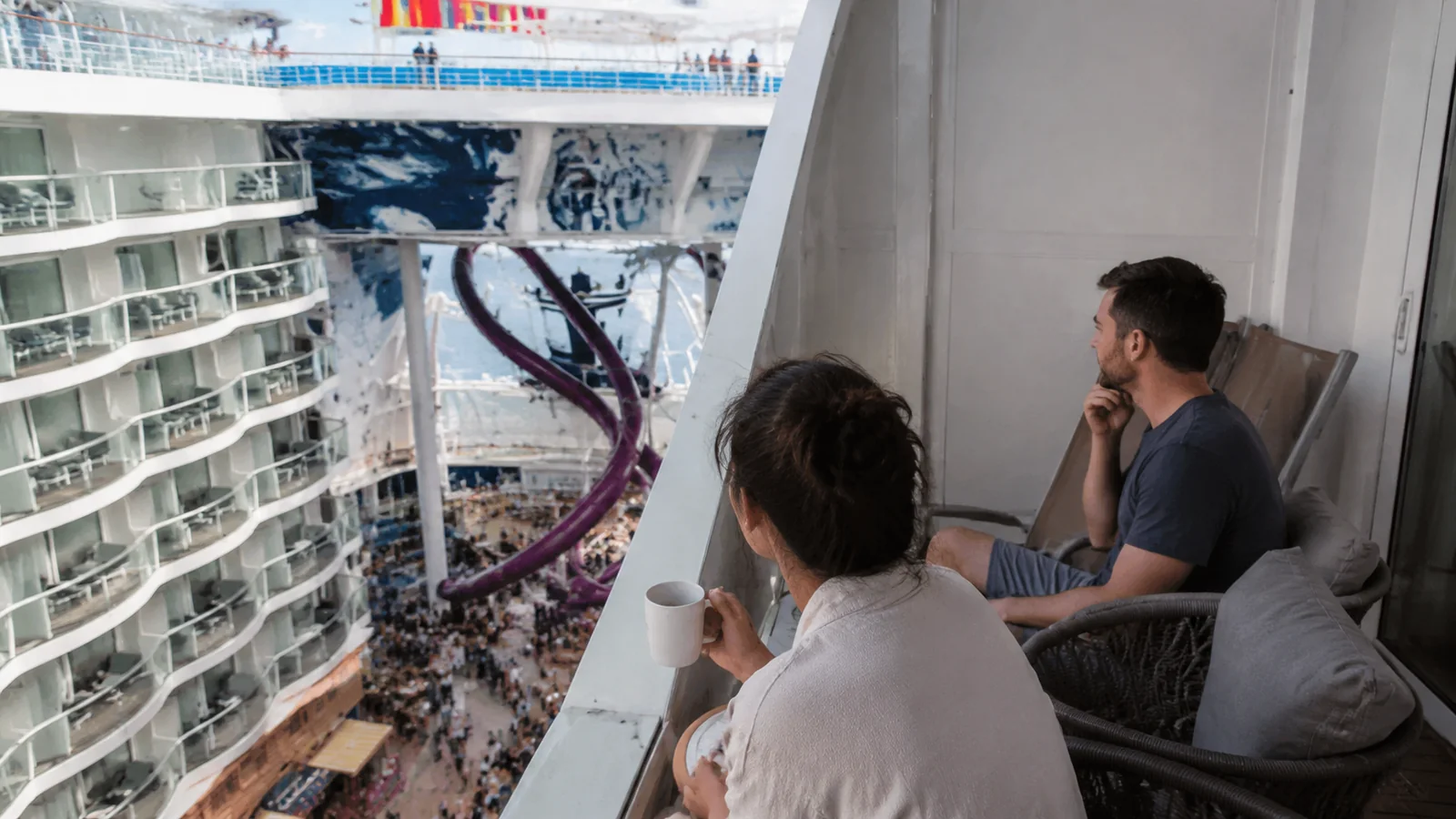 Two passengers looking from a balcony over a busy cruise ship neighborhood
