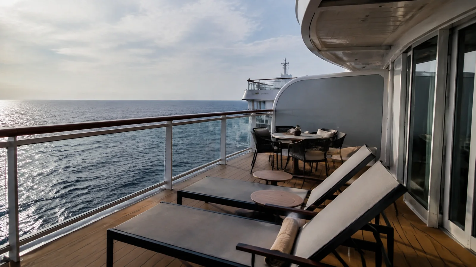 Lounge chairs and a dining table furnish a broad ocean balcony.