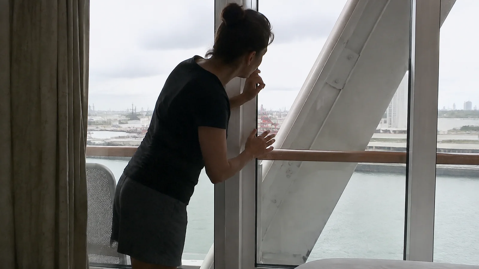 Woman looking around a diagonal support on a cruise ship balcony