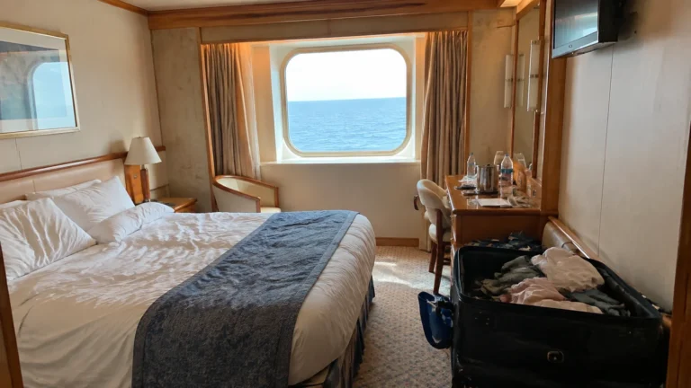 Ocean-view cabin with a double bed and an open suitcase.