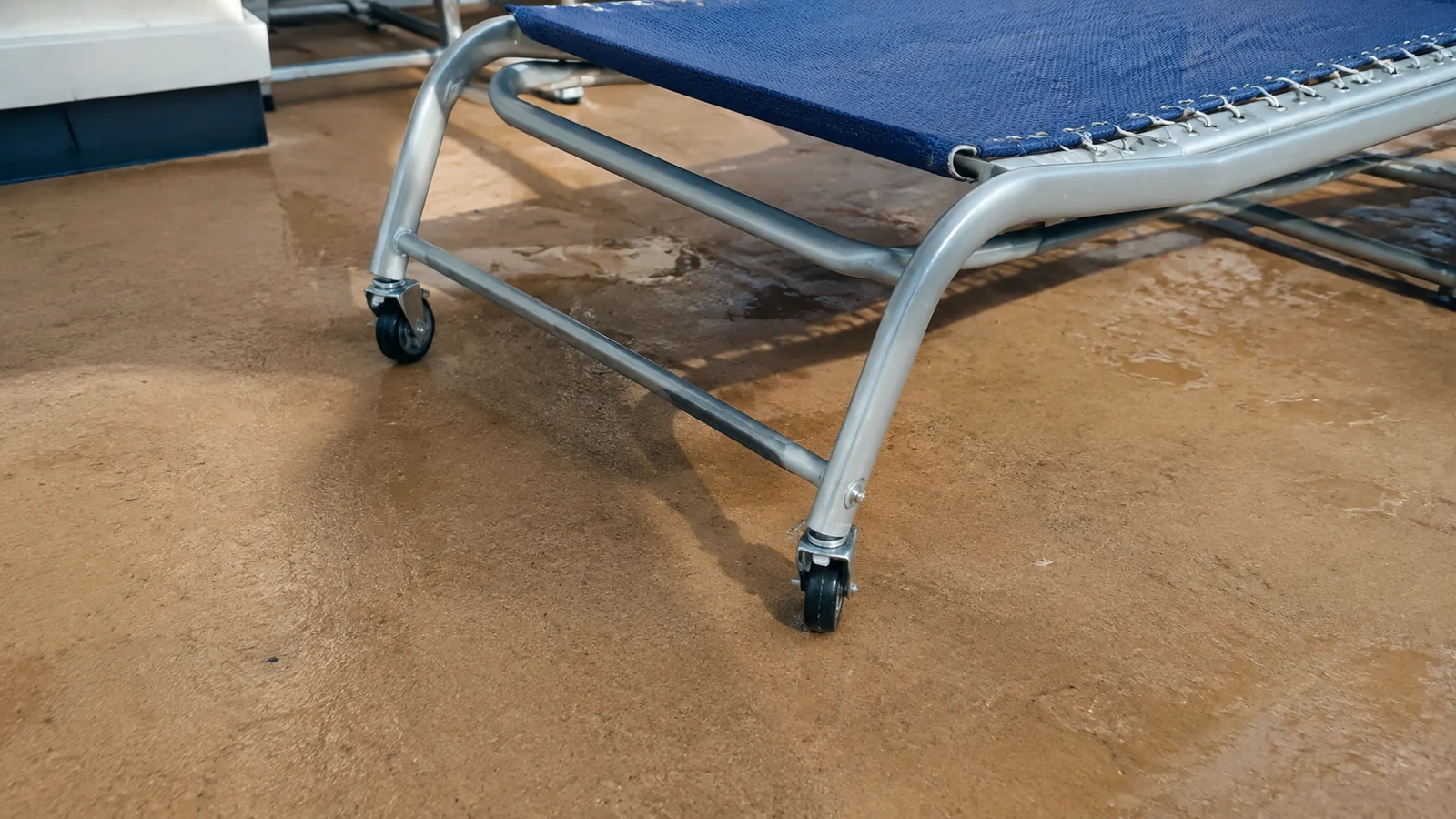 Close-up of a wheeled sun lounger on a ship deck.