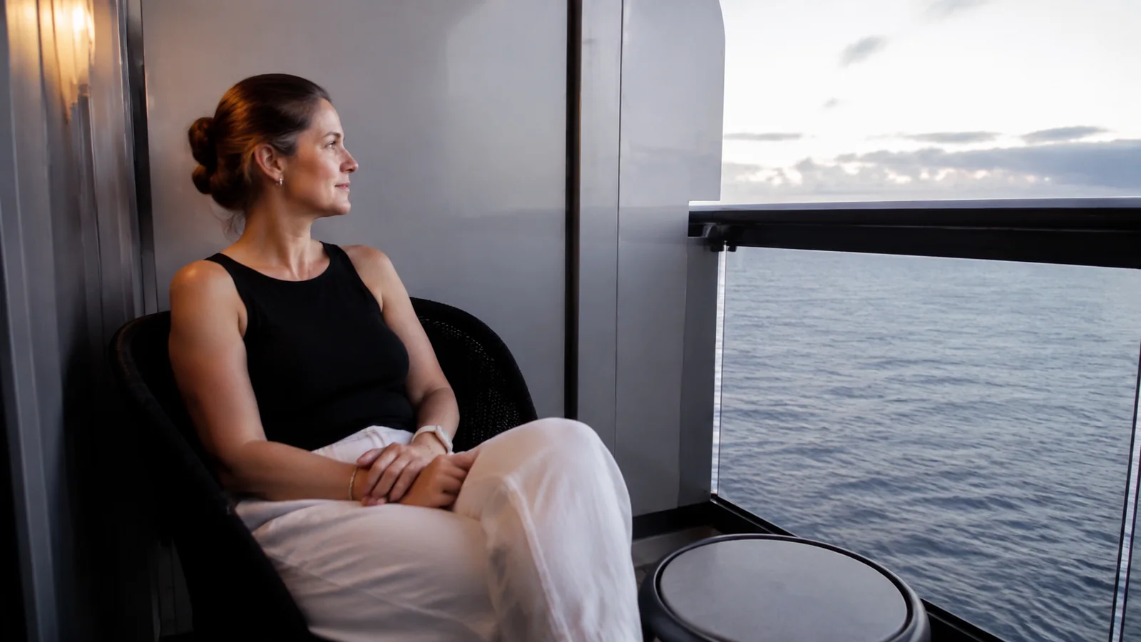 Woman sits on a balcony with hands resting in her lap.