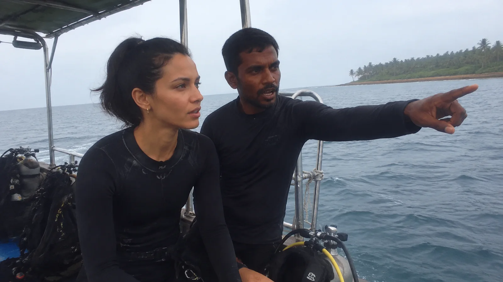 Dive instructor pointing toward the water while briefing a participant.