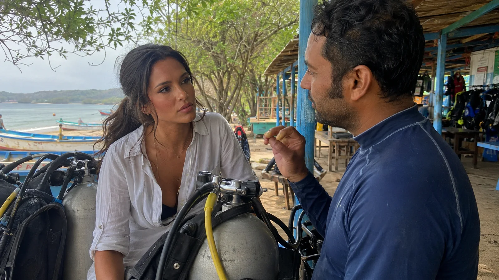 Instructor explaining scuba equipment to a traveler at a dive center.