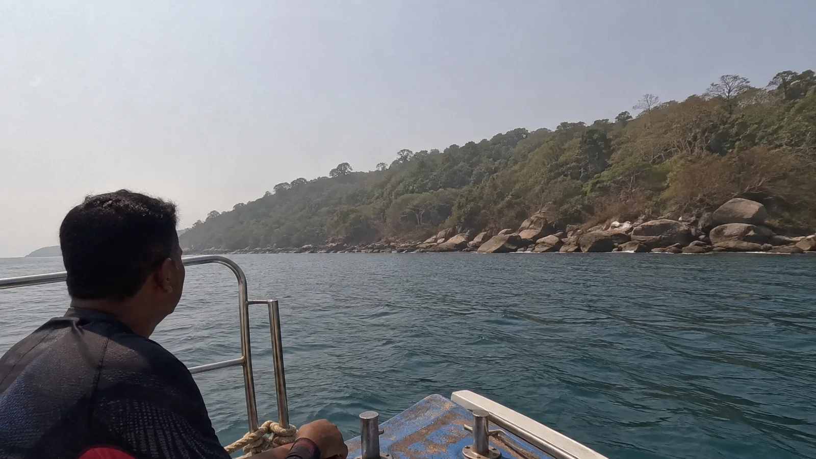 Passenger boat approaching a wooded rocky island.
