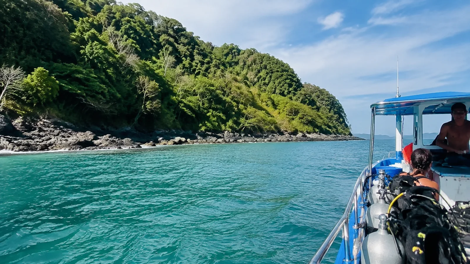 Dive boat beside a lush tropical island in turquoise water.