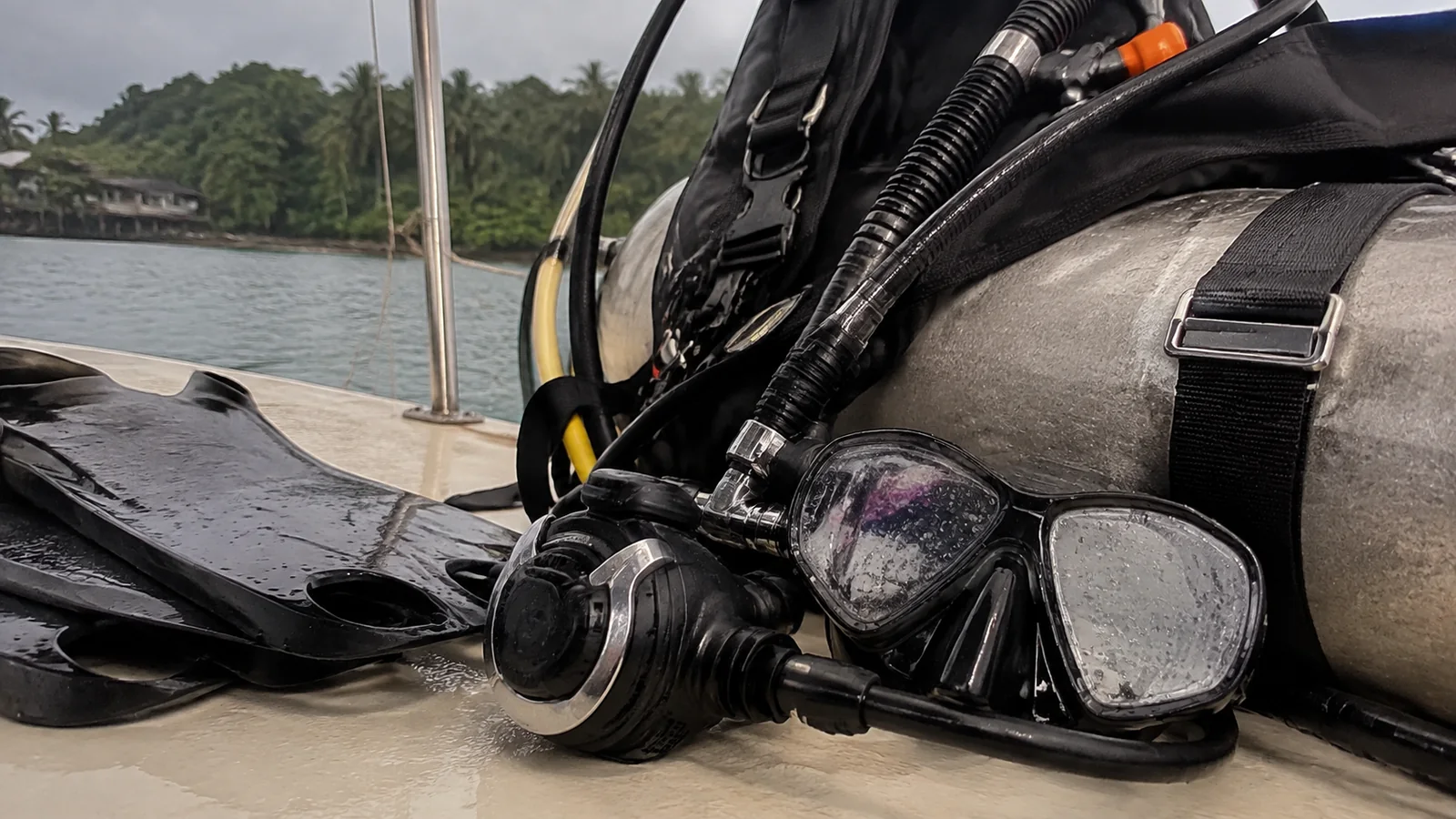 Scuba tank, regulator, mask and fins arranged on a boat.