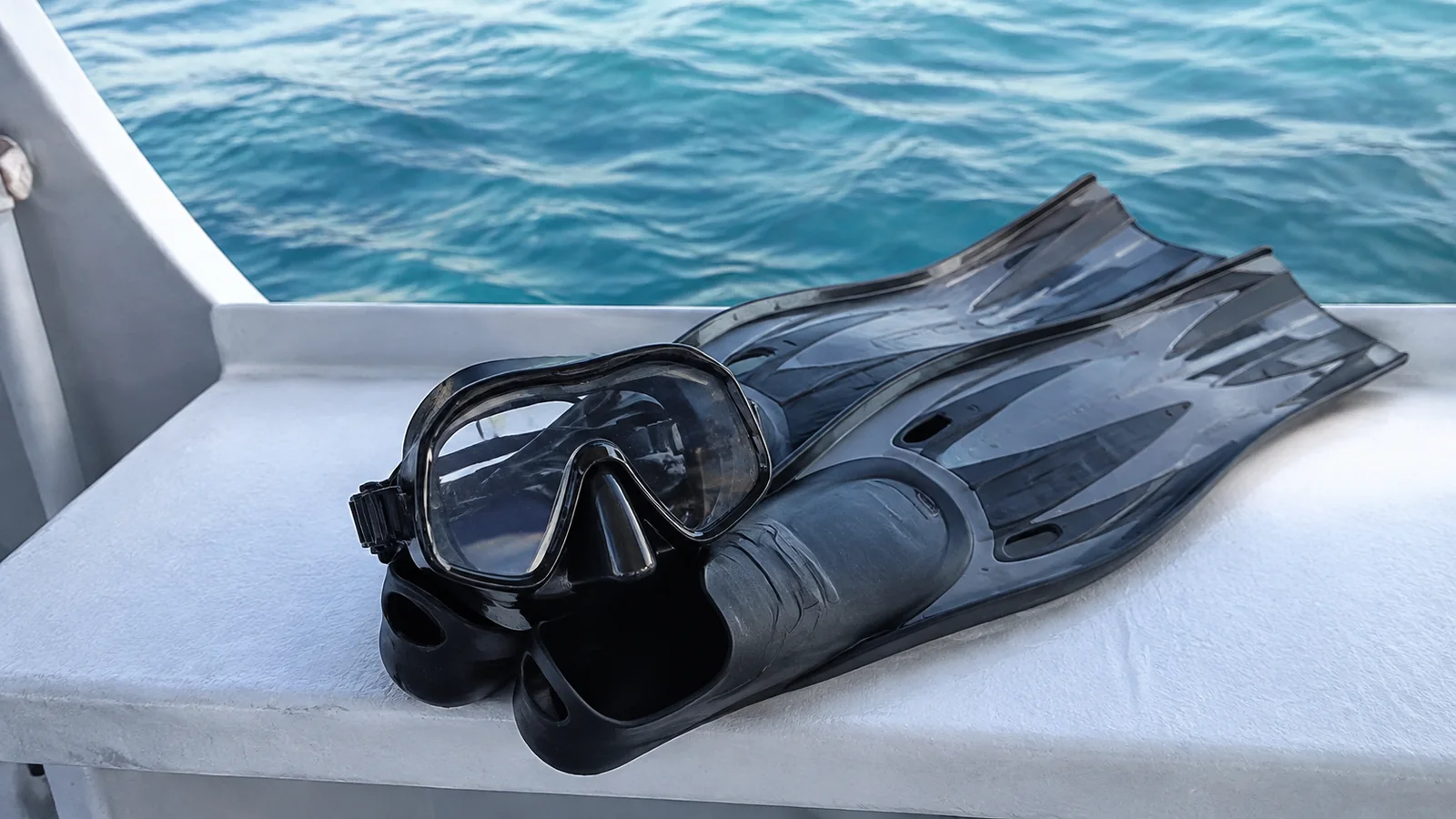 Diving mask and fins arranged on a white boat seat.