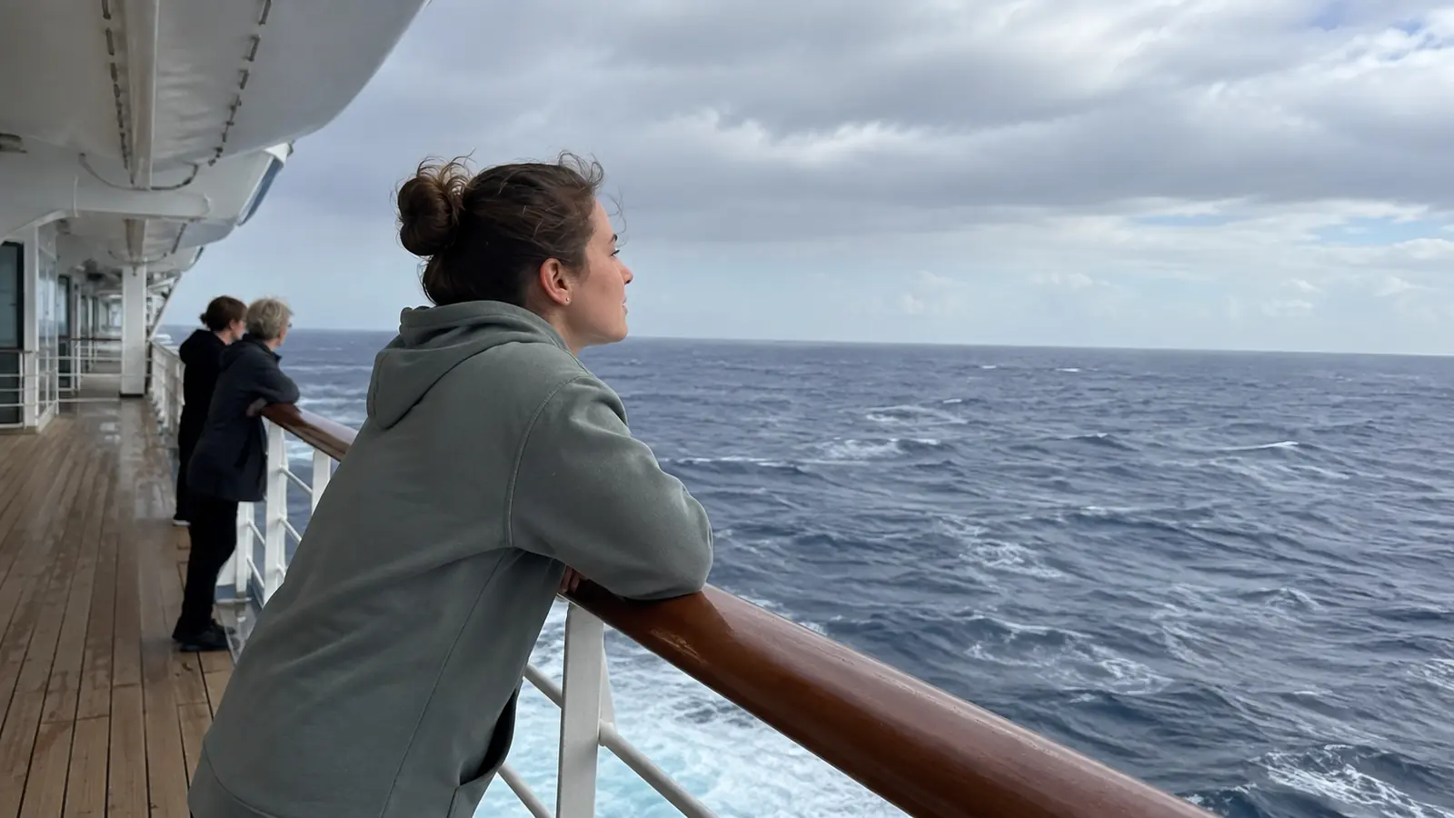 Woman leaning on a cruise ship railing with her head in her hand