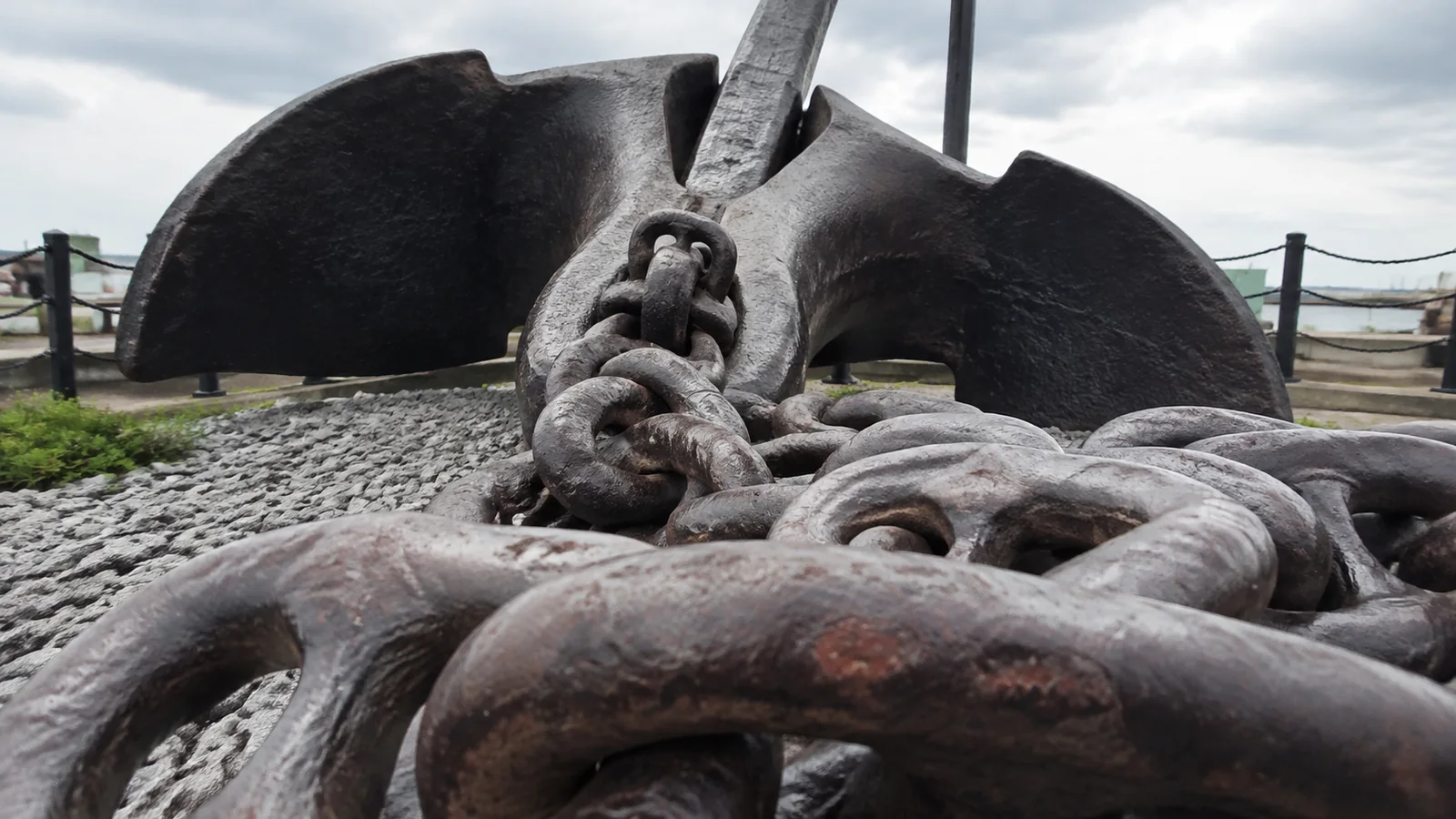 Massive ship anchor and heavy chain displayed outdoors.