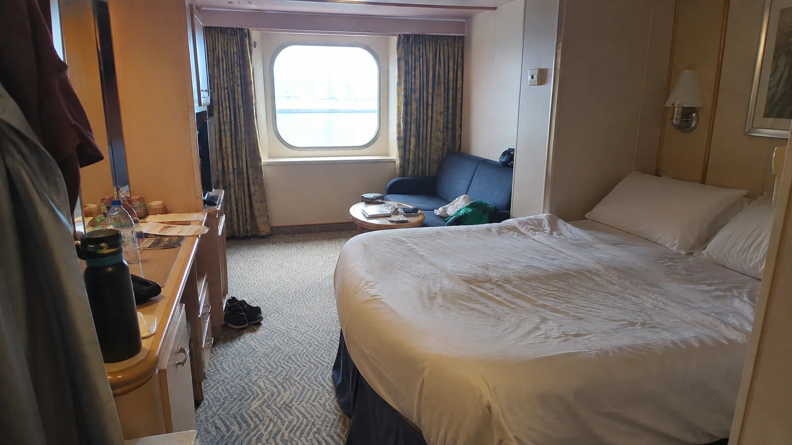Cruise cabin with a double bed and sofa beside a window
