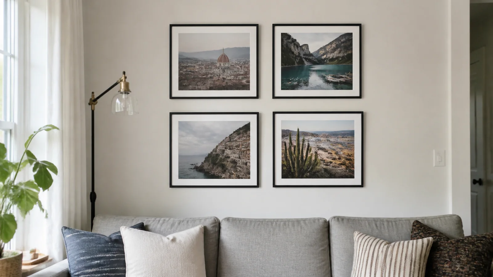 Four framed travel photographs displayed above a gray sofa.